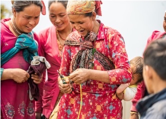 Project Hello World: women with children on their backs use wire cutters to cut wires for the building of a Hello Hub, outdoor solar powered internet hubs, in rural Nepal